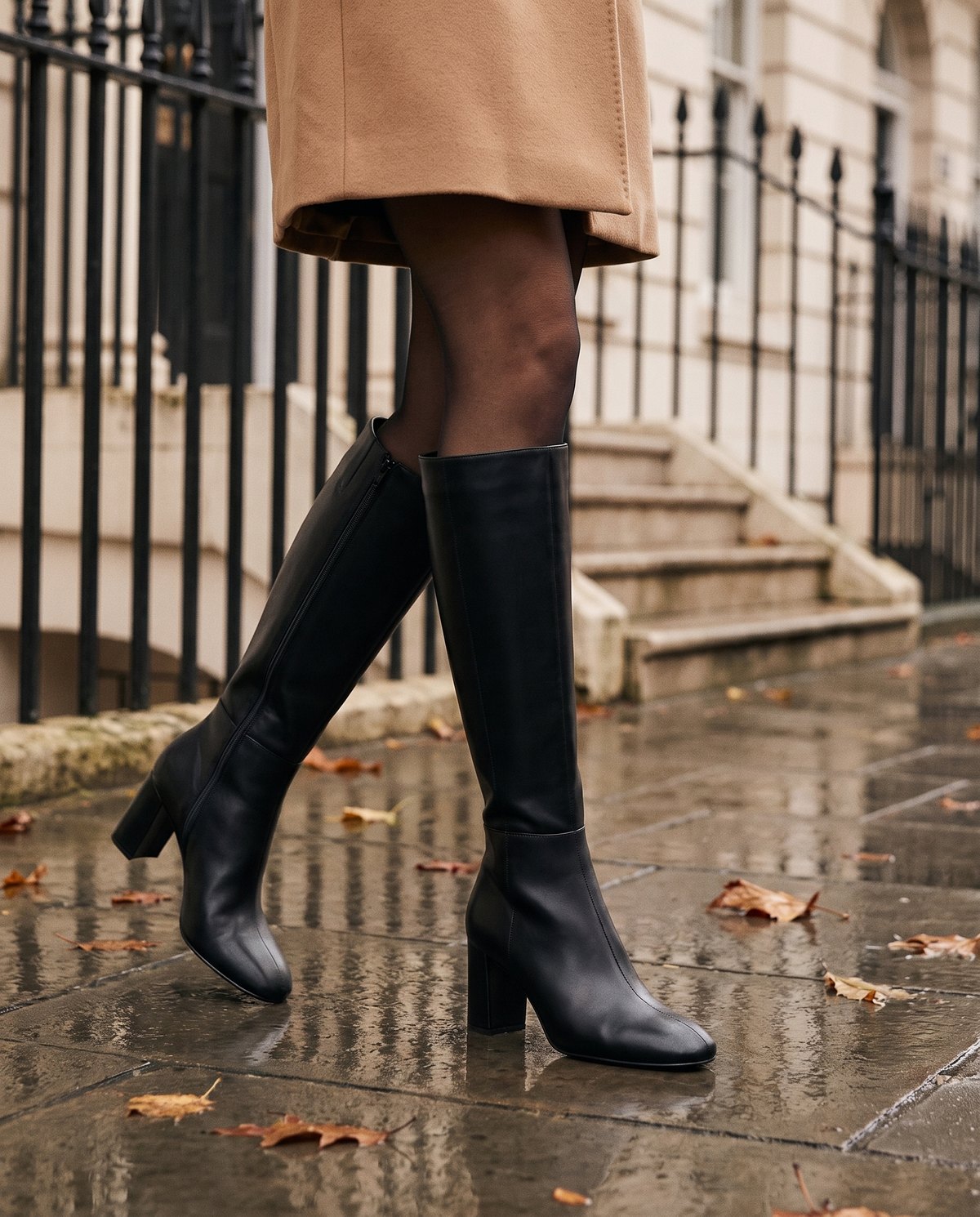 Black knee high boots on a wet pavement